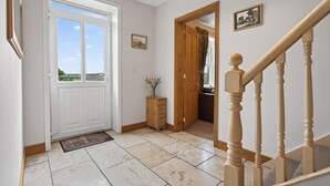 Un pasillo con una puerta blanca, un armario de madera y una escalera con barandilla de madera.