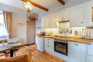 A modern kitchen with white cabinets, a wooden countertop, and various kitchen utensils. - 1 Bed in Whitby (oc-r049) (Robin Hood's Bay)