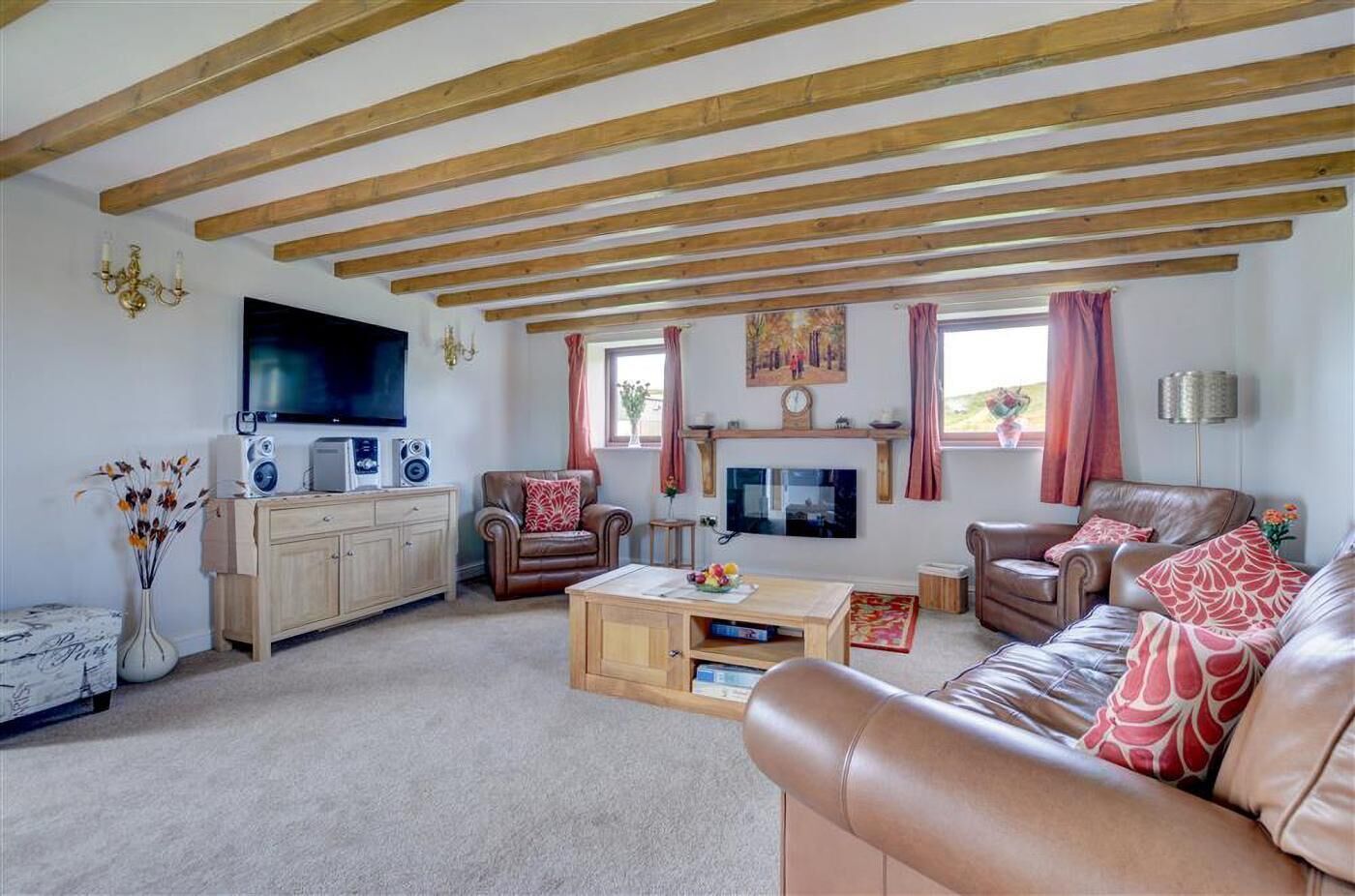 A living room with a wooden ceiling, a TV, a fireplace, and leather furniture.