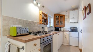 A kitchen with a gas stove, oven, and a built-in toaster. There are wooden cabinets and a refrigerator. - 1 Bed in Great Waldingfield (oc-n33972) (Great Waldingfield)