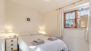 A bedroom with a bed, bedside lamps, a window with curtains, a radiator, and a small picture on the wall. - 1 Bed in Great Waldingfield (oc-n33972) (Great Waldingfield)