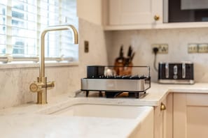 Une cuisine équipée d’un robinet moderne, d’un grille-pain et d’un bloc à couteaux posé sur le plan de travail.