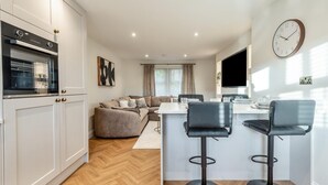Ett modernt kök med en inbyggd ugn och en matplats med en soffa och två barstolar.