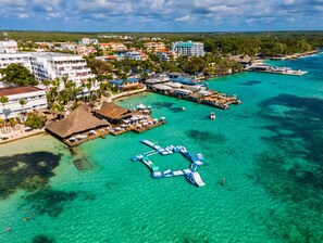 An aerial view of a coastal resort with multiple buildings, a dock area, and clear turquoise waters. - 2- Bedroom Skyrise apartment in Stunning Boca Chica with Breathtaking Oceanview. (Boca Chica)