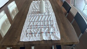 Ein Esstisch mit Stühlen, einer weißen Tischdecke und einer dekorativen Vase.