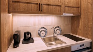 A kitchen with wooden cabinets, a stainless steel sink, a coffee maker, and a kettle. - Urban Residence: Stylish comfort with city views in the heart of Piraeus. (Pireas)