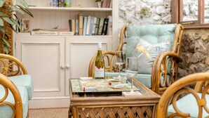 A cozy room with wicker chairs, a table with a board game, a bottle of wine, and bookshelves. - 2 Bed in Kingsteignton (oc-w34194) (Kingsteignton)