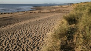A sandy beach with a wooden fence and grassy dunes. - 2 Bed in Kingsteignton (oc-w34194) (Kingsteignton)