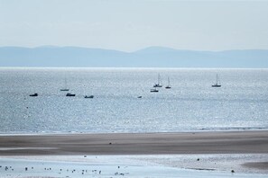 Una playa con barcos en el agua y una orilla arenosa.