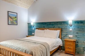 Ein Schlafzimmer mit einem hölzernen Bett, einem Nachttisch, einer Wandlampe und einem gerahmten Bild.