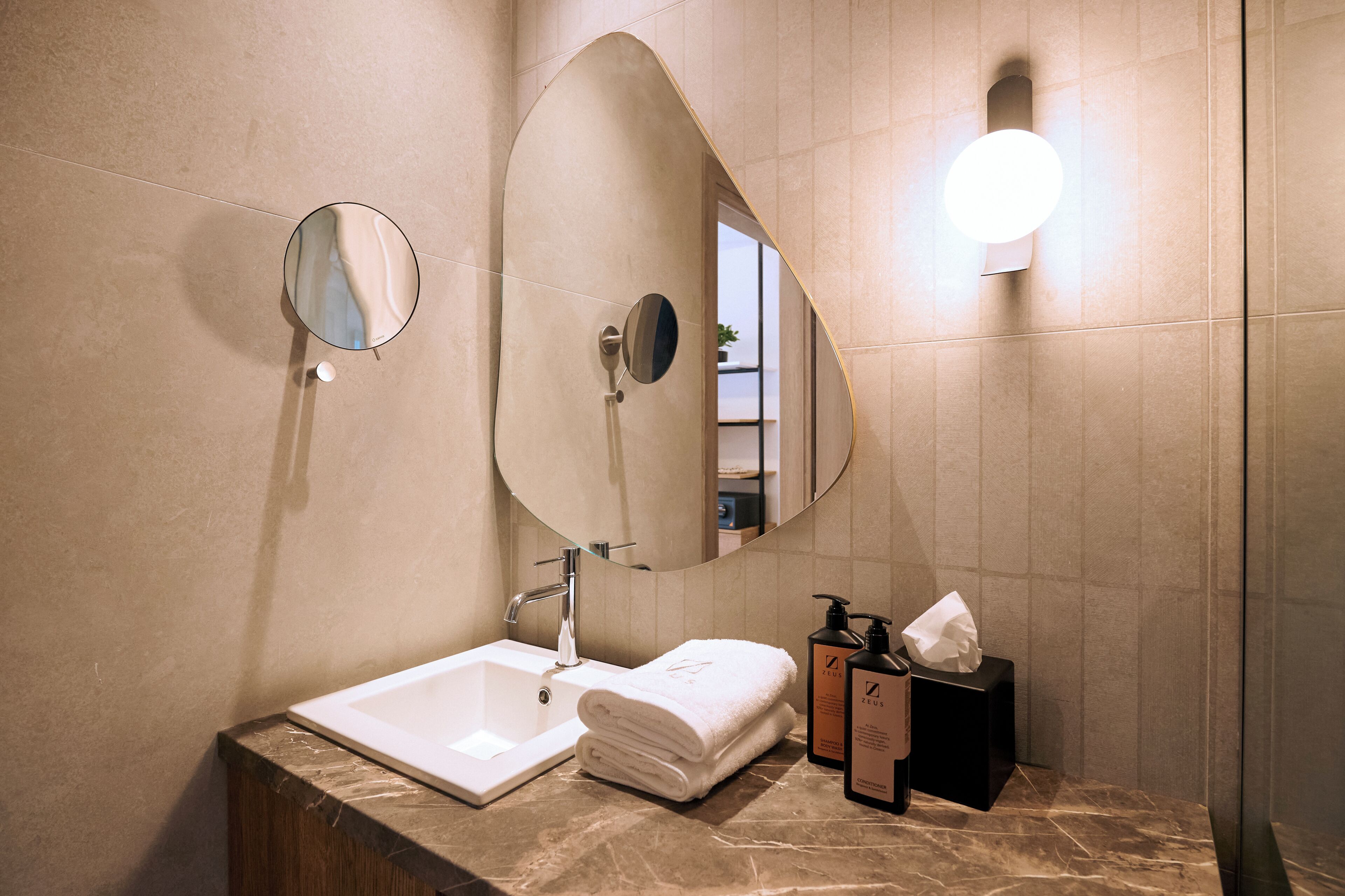 A bathroom with a sink, mirror, towel, and toiletries.