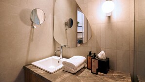 Ein Badezimmer mit Waschbecken, Spiegel, Handtuch und Pflegeprodukten.