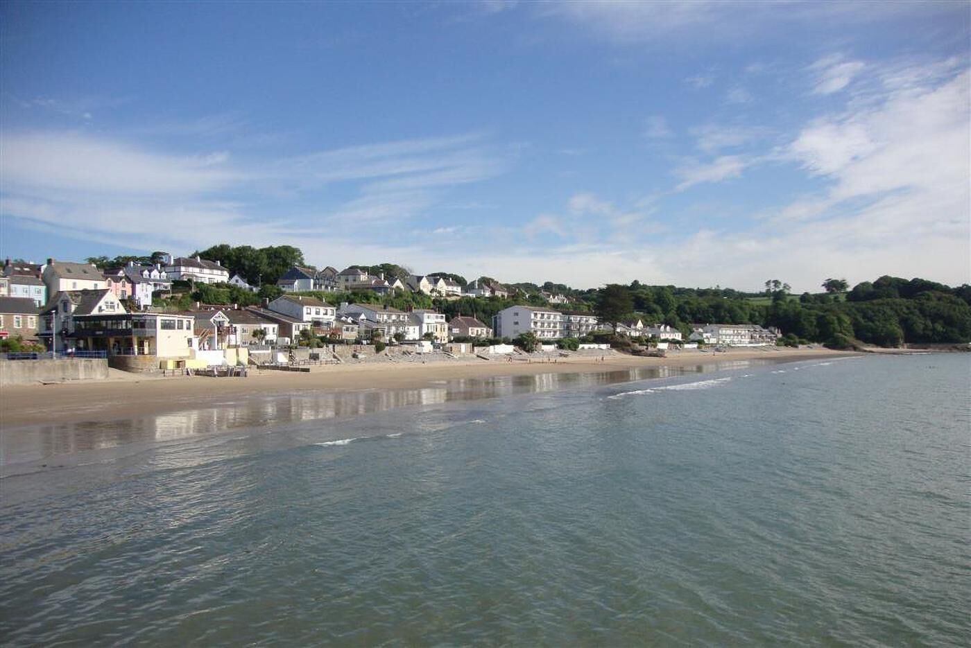 A coastal town with beachfront houses, a sandy beach, and a calm sea.