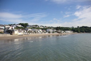 Une ville côtière avec des maisons donnant sur la plage, une plage de sable et une mer calme.