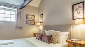 A neatly made bed with a white duvet, two pillows, and a blanket. There are two bedside tables with lamps and a framed picture on the wall. - 3 Bed in Bamburgh (oc-t34385) (Bamburgh)