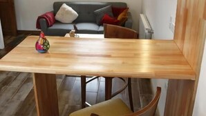 Un coin repas avec une table et des chaises en bois, un luminaire suspendu et un canapé en arrière-plan.
