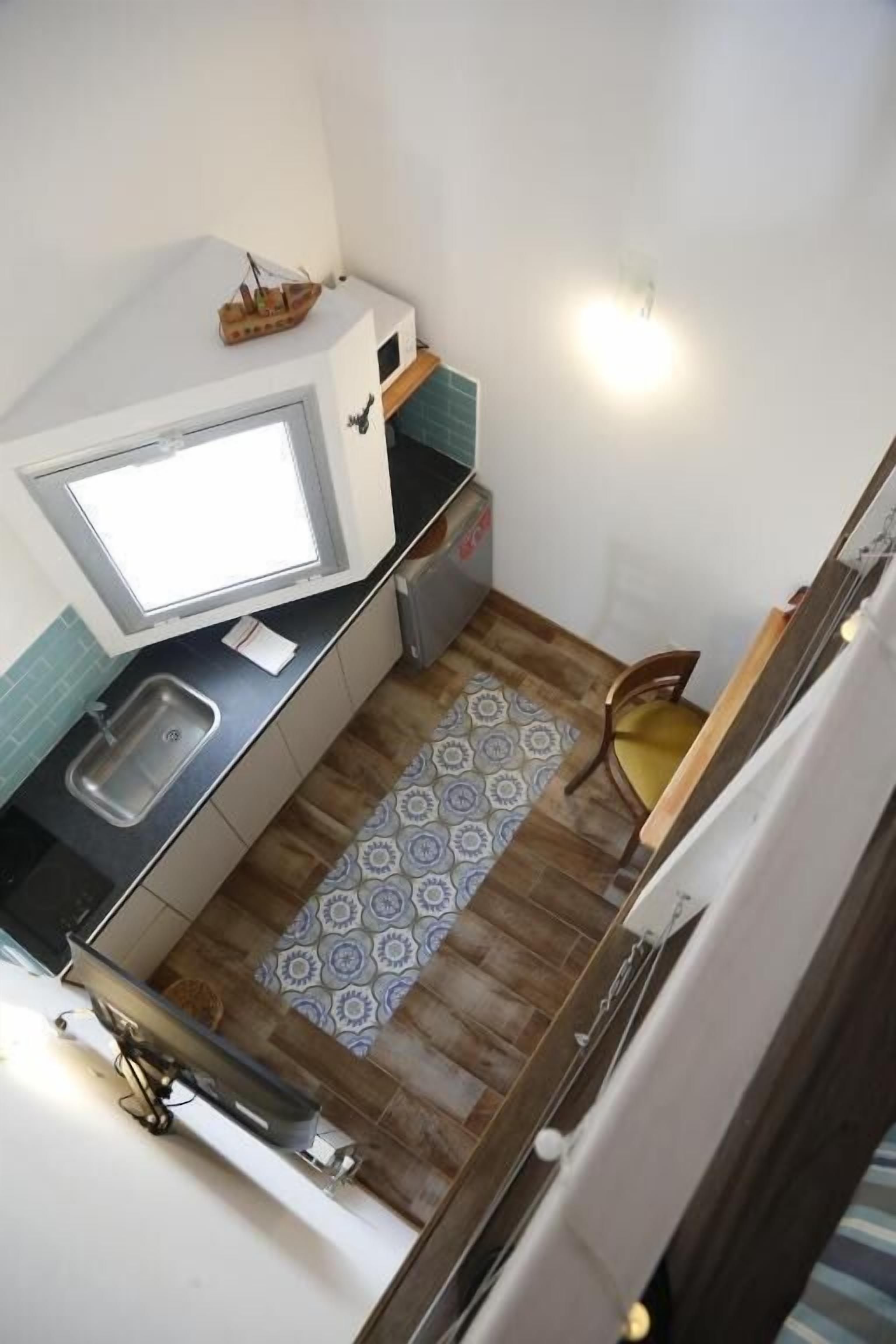 Una cocina compacta con ventana, lavamanos y un refrigerador pequeño.