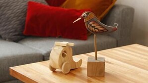 A wooden table with a wooden bird sculpture and a wooden horse sculpture.