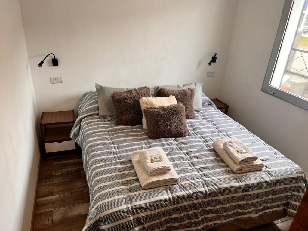 Cama com roupa de cama listrada, duas almofadas e duas toalhas dobradas.
