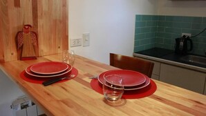 Une table de salle  à manger en bois, avec de l’assiette et des couverts rouges, un verre et une sculpture en bois.