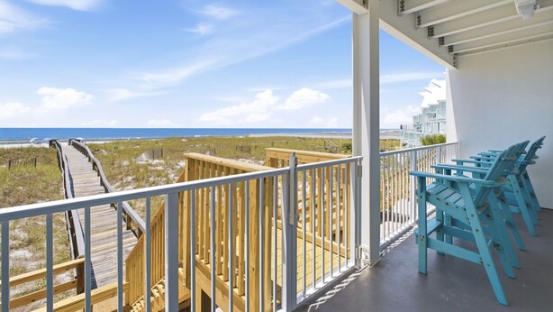 A balcony with a view of the beach and ocean, wooden railings, and blue chairs. - Welcome to Rivieria Dunes #102 (Perdido Key)