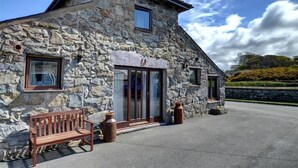 Un bâtiment en pierre avec un banc en bois et deux grandes fenêtres.
