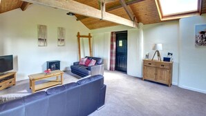 A living room with a sofa, a wooden coffee table, a television, and a fireplace. - 1 Bed in Llandinam (oc-waa376) (Llandinam)
