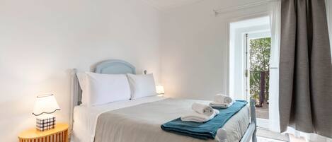 Ein Schlafzimmer mit Bett, Nachttischlampe und Blick ins Freie.