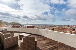 A rooftop terrace with wicker furniture and a city view. - Panorama View Apartment in Amazing Viewpoint (Lisbon)
