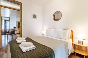 A hotel room with a bed, a round mirror, a bedside lamp, and a view of a dining area. - Lisbon Panorama View Apartment (Lisbon)