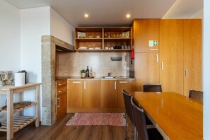 A modern kitchen with wooden cabinets, a dining table, and a kitchen island. - Lisbon Panorama View Apartment (Lisbon)
