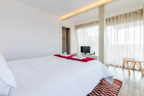 A hotel room with a large bed, a television, a wooden chair, and a window with curtains. - Lisbon Panorama Apartment in Lisbon's Best Views (Lisbon)