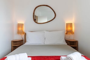 A neatly made bed with white linens, two bedside lamps, and a round mirror on the wall. - Panorama View Apartment in Beautiful Viewpoint (Lisbon)