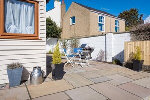 Eine Terrasse mit Grill, Stühlen und Kübelpflanzen.