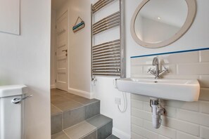 Ein Badezimmer mit einem weißen Waschbecken, einem Spiegel und einem Handtuchhalter.