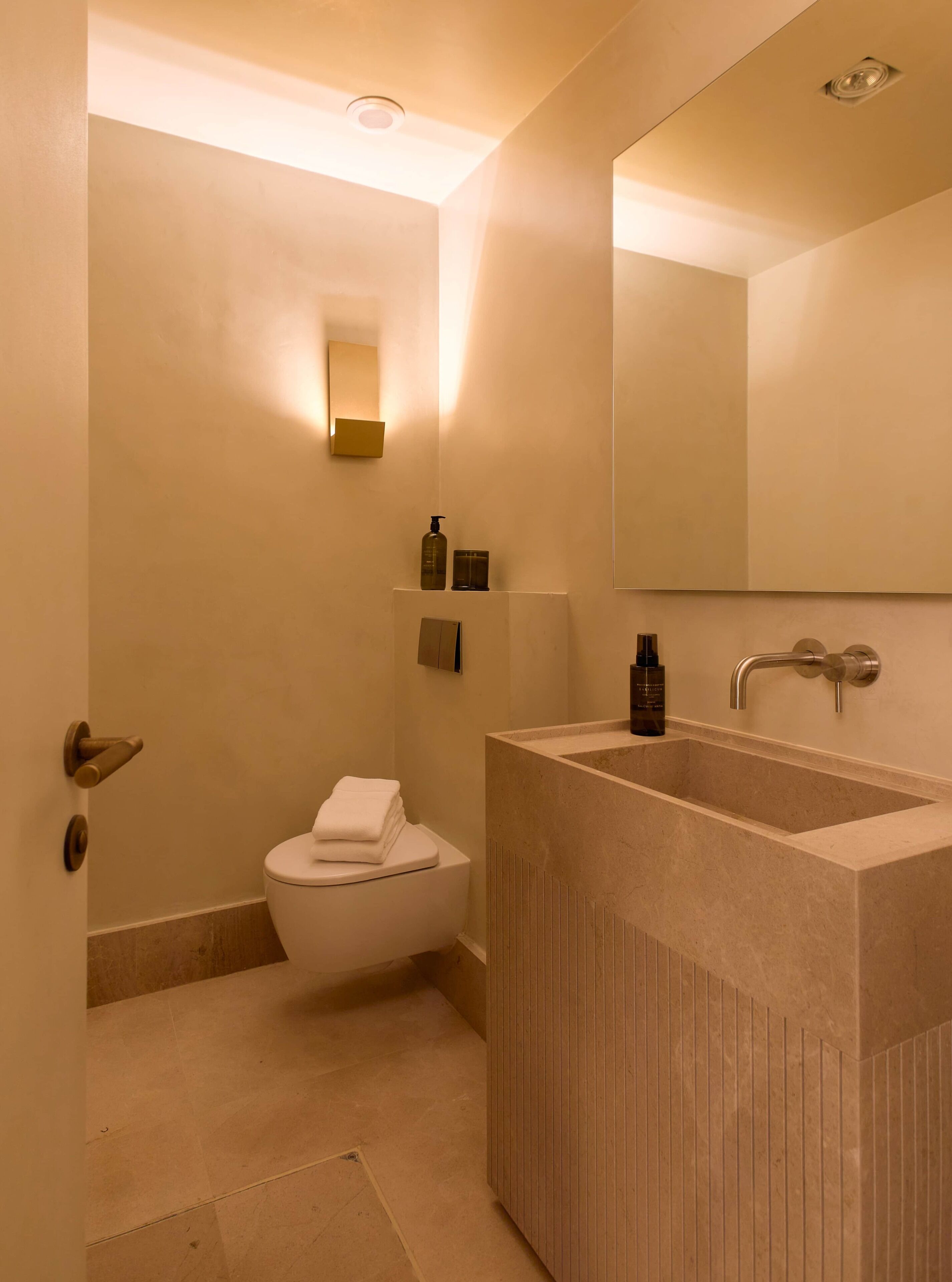 Een badkamer met toilet, wastafel en spiegel.