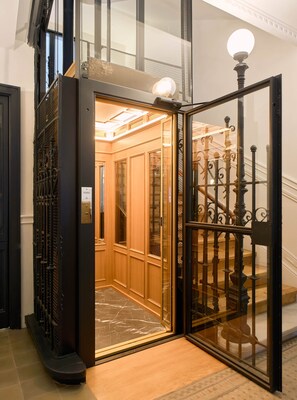 An elevator with a glass door, a metal gate, and a wooden interior. - Príncipe Signature Residence (Madrid)