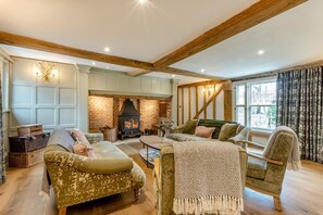 A cozy living room with a fireplace, wooden beams, comfortable seating, and a view of the outdoors. - 11 Bed in Stebbing (oc-p34450) (Stebbing Green)