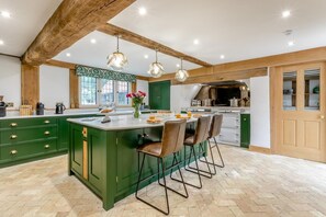 A kitchen with a large island, wooden beams, pendant lights, and a view of the outside. - 11 Bed in Stebbing (oc-p34450) (Stebbing Green)