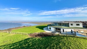 Ein modernes Haus mit einer gewölbten Dachform, großen Fenstern und Meerblick.