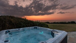 Un bain à remous dans un jardin offrant une vue sur le coucher de soleil.