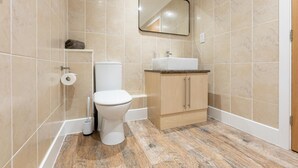 Une salle de bain avec des toilettes, un lavabo, un miroir et des murs carrelés.