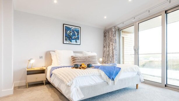 Une chambre moderne avec un lit, une table de chevet, un bureau, une fenêtre donnant sur un beau paysage et un tableau accroché au mur.