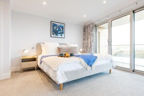 Une chambre moderne avec un lit, une table de chevet, un bureau, une fenêtre donnant sur un beau paysage et un tableau accroché au mur.