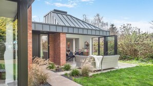 Een modern huis met een glazen tuinkamer, een eetgedeelte en een tuin.