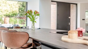 Een moderne keuken met een groot eiland, een vaas met bloemen en een eethoek met stoelen en een tafel.