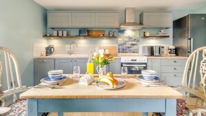 Une cuisine équipée d’une table à manger pour deux personnes, d’une cuisinière, d’un four à micro-ondes et d’un réfrigérateur.