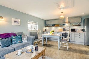 A cozy living room with a sofa, coffee table, and a dining area with a table and chairs. - 1 Bed in Happisburgh (oc-b34458) (Happisburgh Common)