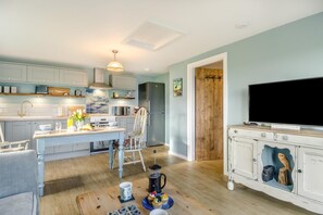 A modern kitchen with a dining area, a TV, and a wooden door. - 1 Bed in Happisburgh (oc-b34458) (Happisburgh Common)