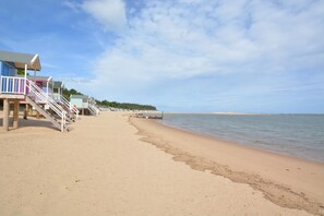 A beach with a wooden staircase leading to a building with a blue roof and white railings. - 2 Bed in Wells-next-the-Sea (oc-1025) (Wells-next-the-Sea)